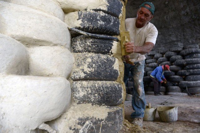 TO GO WITH AFP STORY BY PAULA CARRILLO FILES - Picture taken on March 16, 2015, shows a man who works building a house with tires in Choachi, Cundinamarca, Colombia on March 16, 2015. In the same way as igloos, thermally efficient and resistant to quakes, a particular kind of house in central Colombia takes advantage of a material which is thrown away: tires. 5.3 million tires are thrown away each year in Colombia, and since they take millions of years in decomposing, using them for building becomes a potential.  AFP PHOTO / Eitan Abramovich