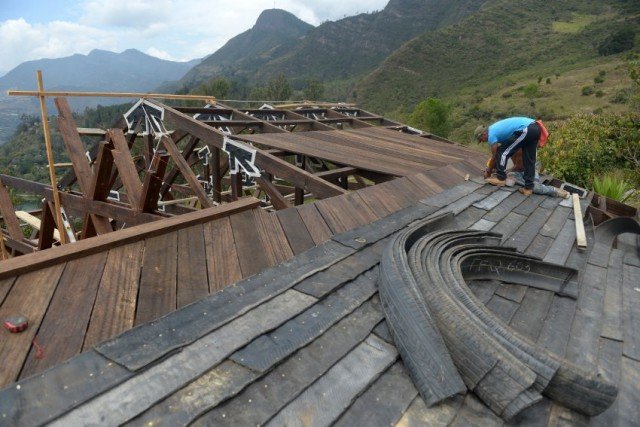Men work building a house with tires in Choachi, Cundinamarca, Colombia on March 16, 2015. In the same way as igloos, thermally efficient and resistant to quakes, a particular kind of house in central Colombia takes advantage of a material which is thrown away: tires. 5.3 million tires are thrown away each year in Colombia, and since they take millions of years in decomposing, using them for building becomes a potential.  AFP PHOTO/Eitan Abramovich