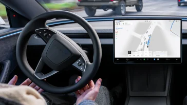 Салон електромобіля Tesla з активним інтерфейсом автопілота FSD Supervised на центральному екрані під час руху вулицями міста